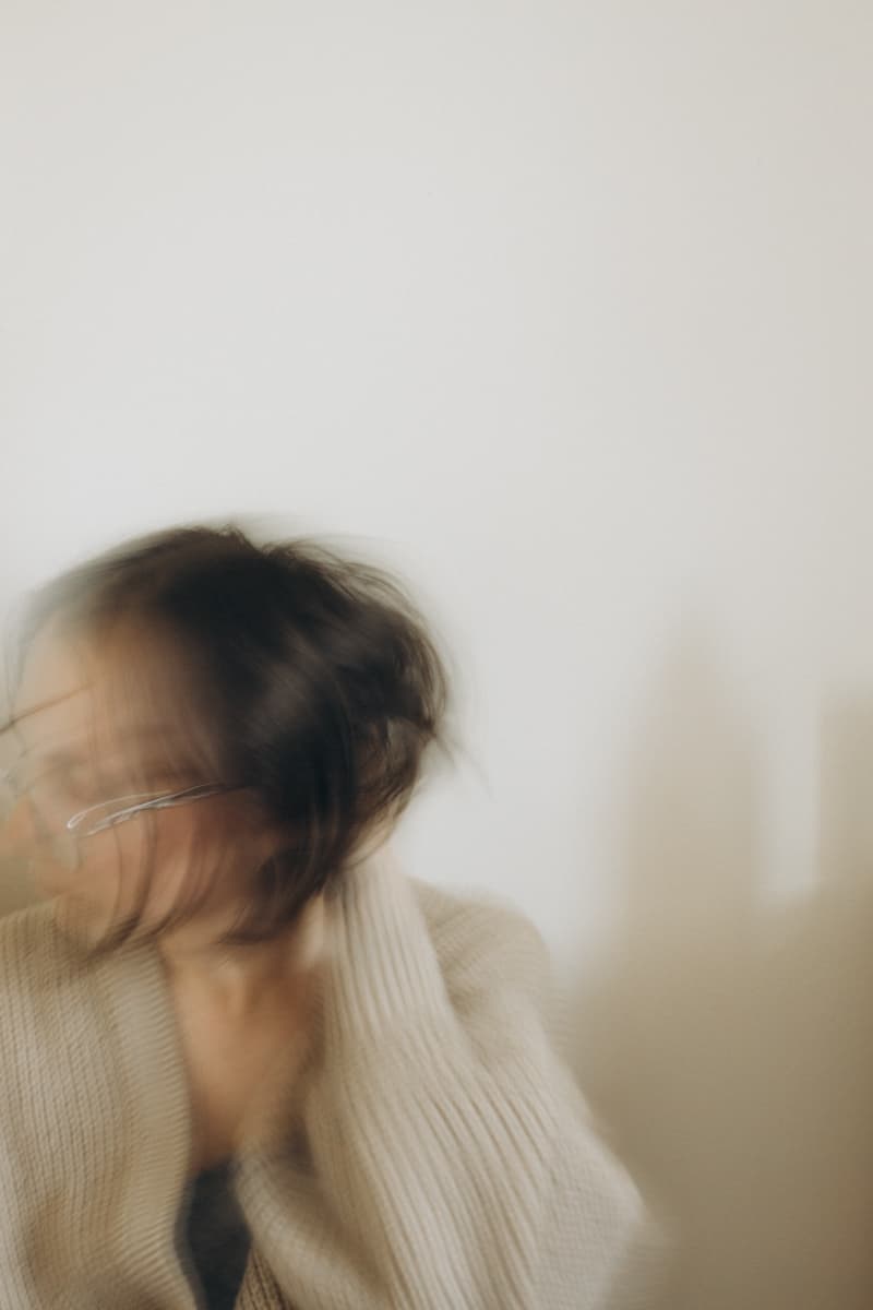 Self-portrait in a cream cardigan, head turning in motion blur
