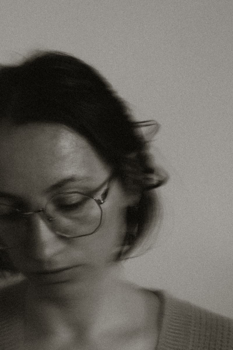 Black-and-white self-portrait, eyes lowered behind glasses